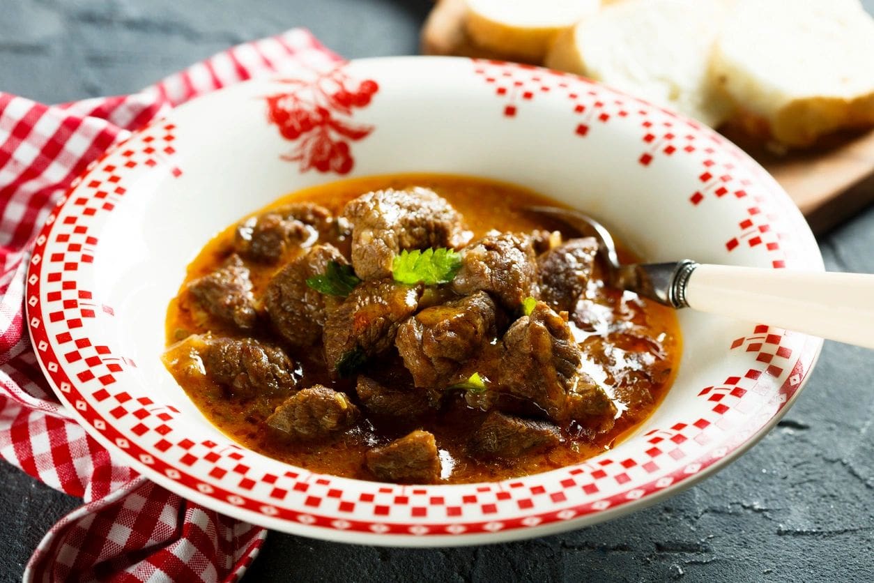 A bowl of stew with meat and gravy.